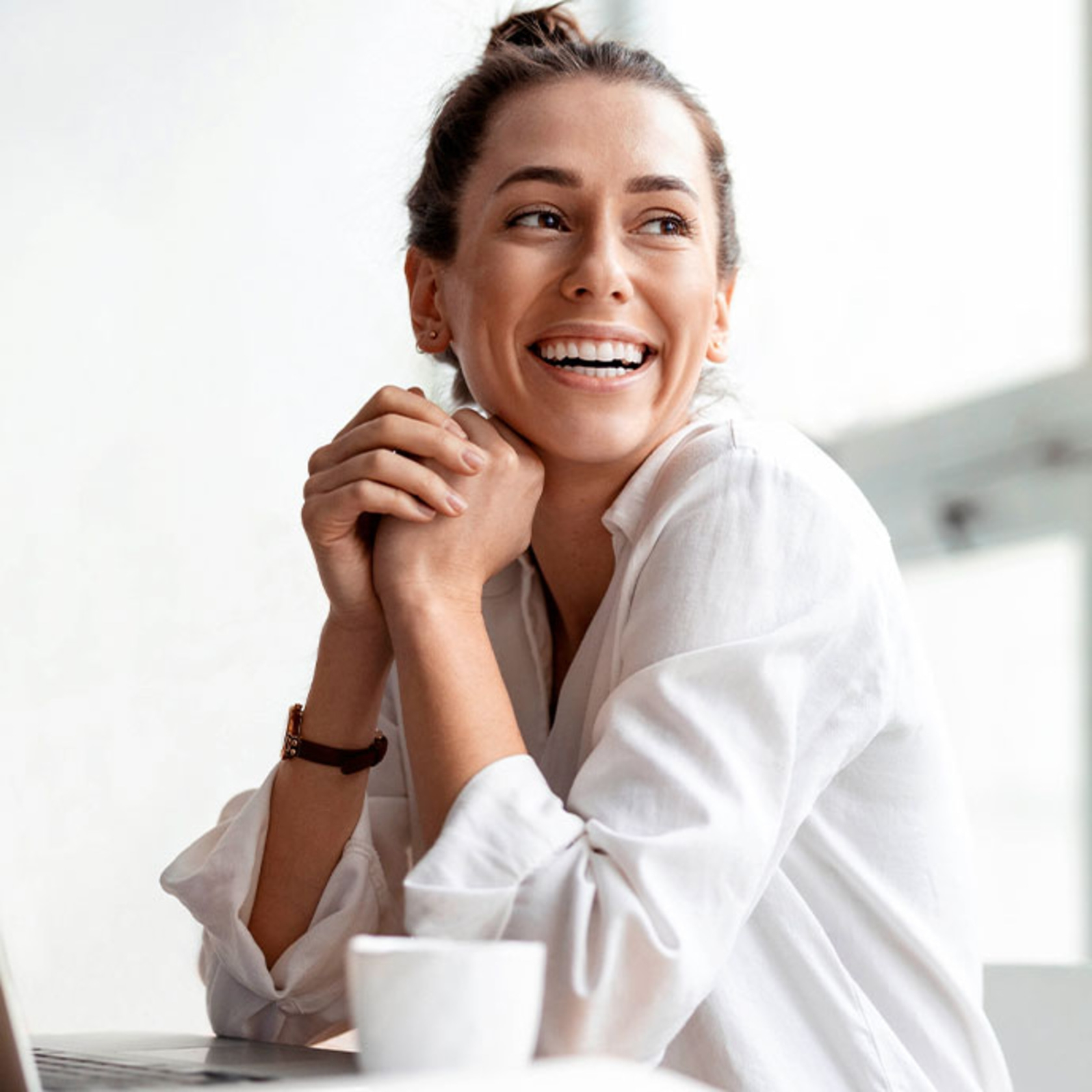 Mujer sonriente con las manos bajo la barbilla, de aspecto pensativo y feliz.