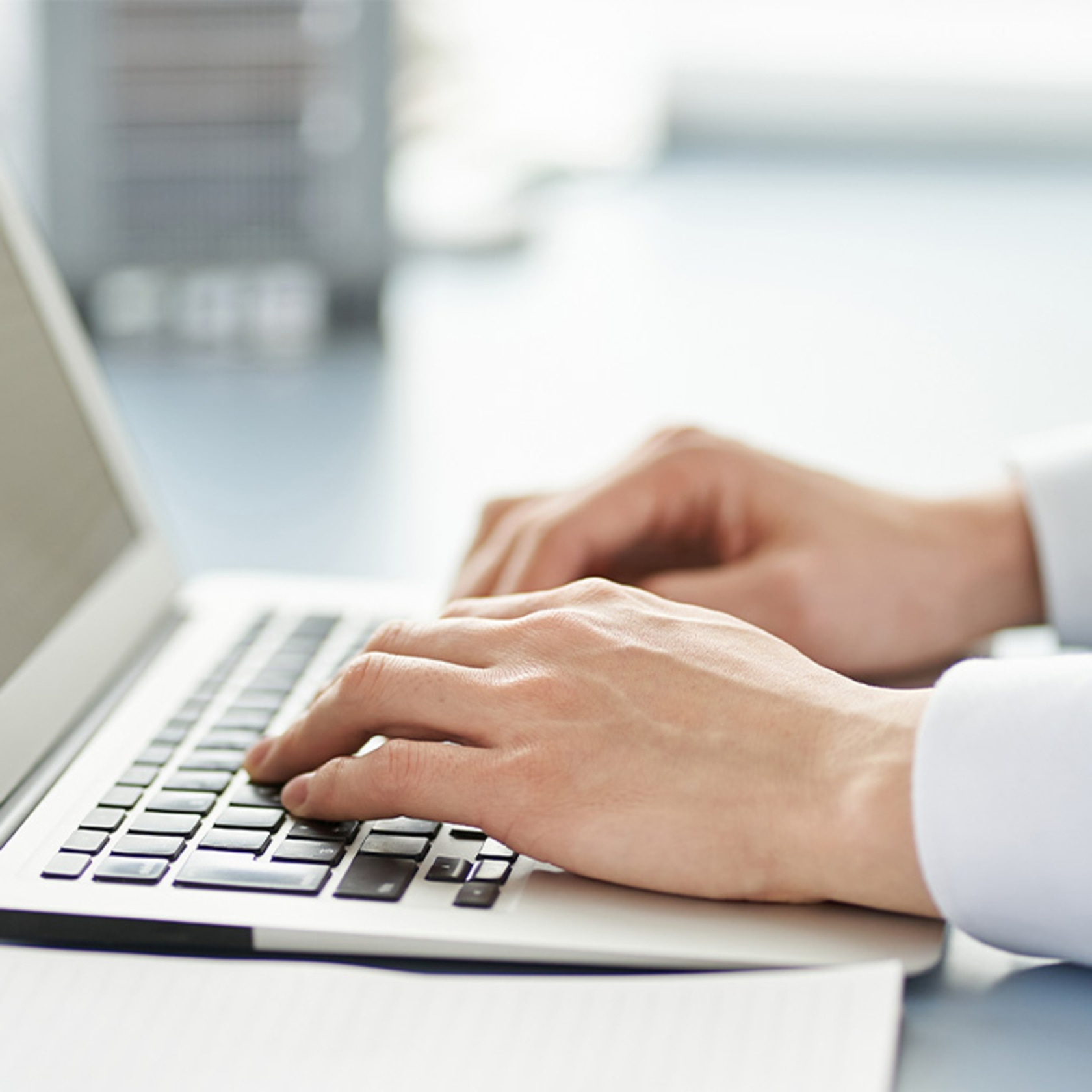 Close-up of hands typing on a laptop keyboard, work in progress.