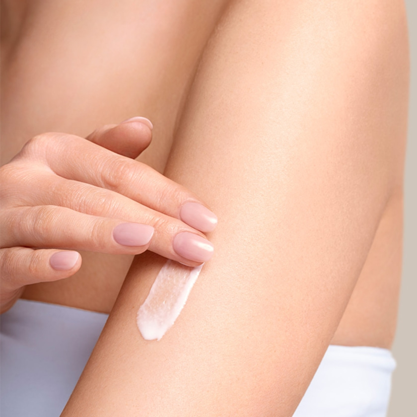 Nahaufnahme einer Person, die Creme auf ihren Arm aufträgt, Hautpflegekonzept.