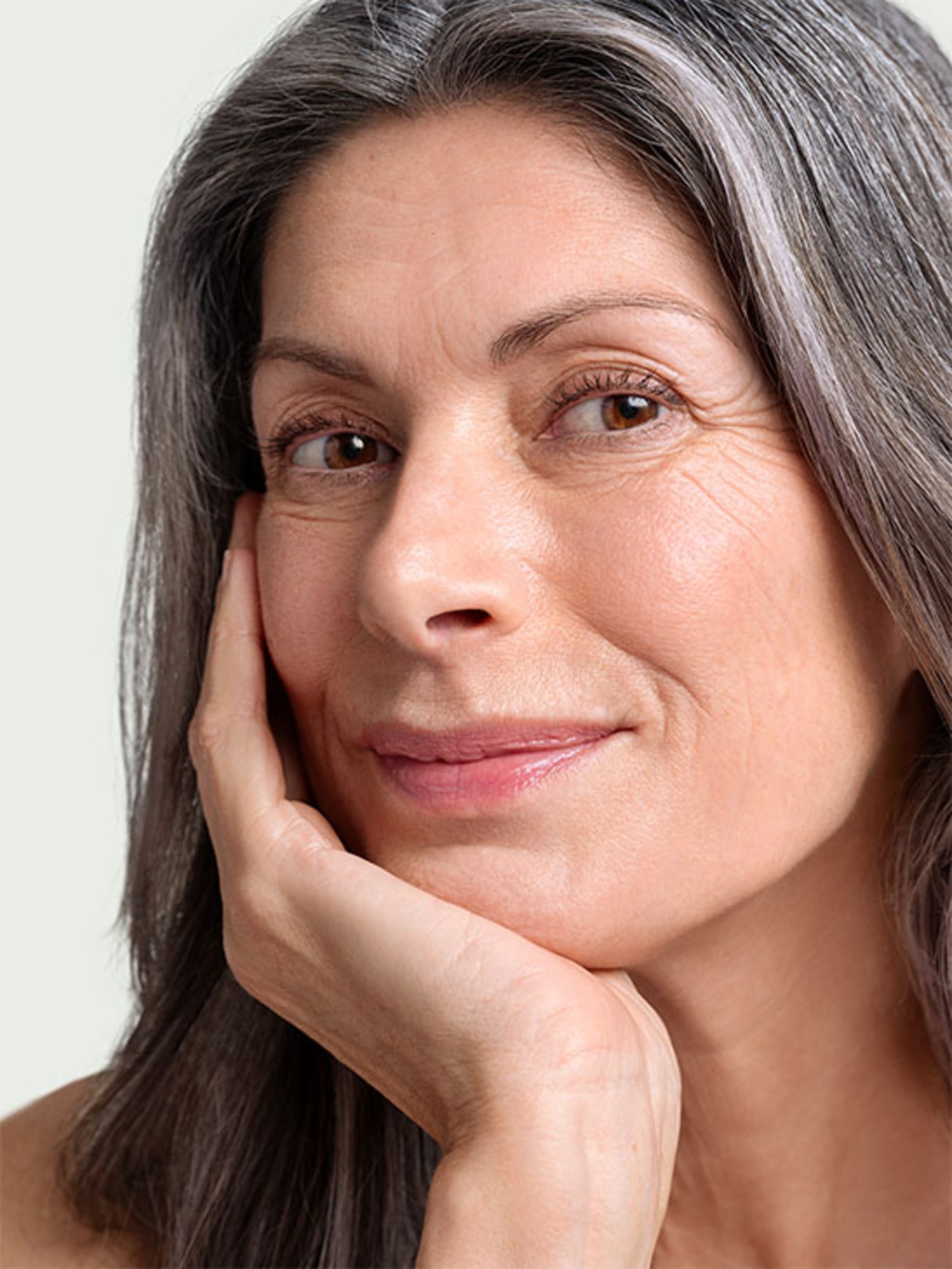 Portrait of an older woman with gray hair smiling at the camera, posing.