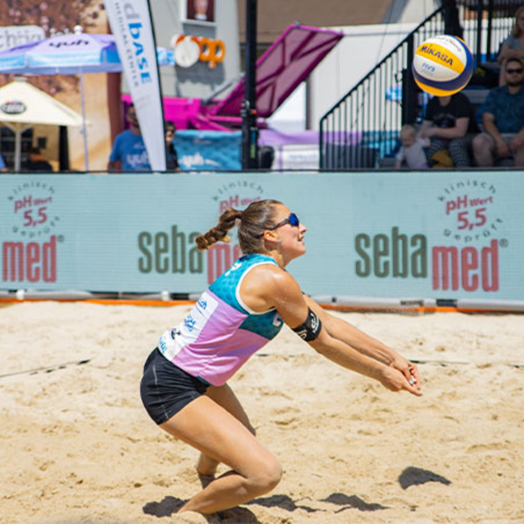 Beach volleyball player hitting a ball, with logos in the background.