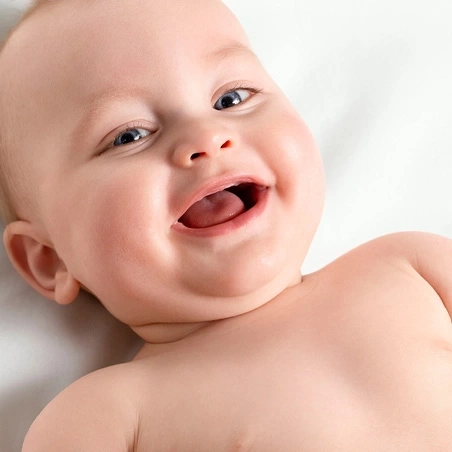 Happy baby smiling at camera, mouth open, tongue visible, joyful expression.
