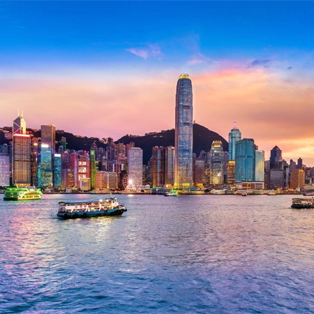 Hong Kong skyline with boats on water at sunset with colorful sky