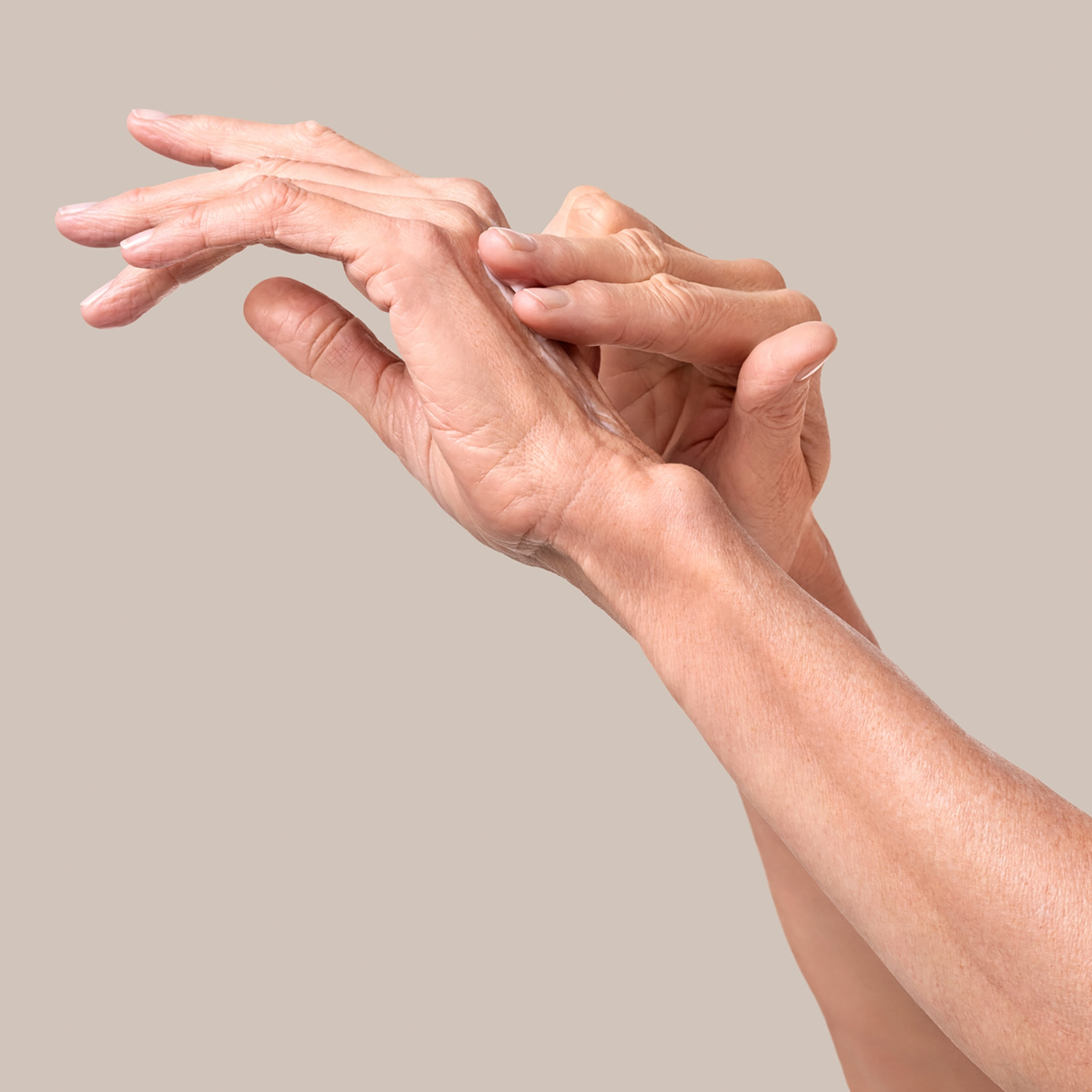 Close-up of hands touching each other on a beige background, wrinkled skin