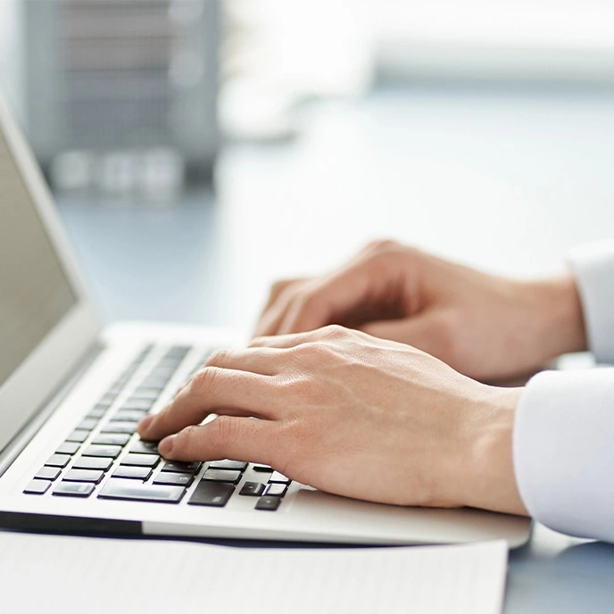 Close-up of hands typing on a laptop keyboard, work in progress.