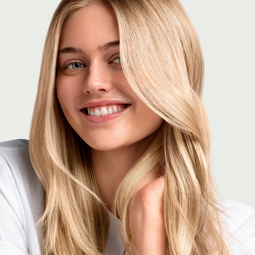 Young blonde woman smiling at the camera, close-up, long hair, white shirt