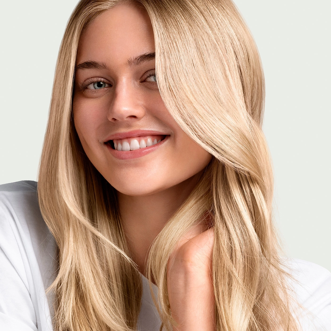 Young blonde woman smiling at the camera, close-up, long hair, white shirt
