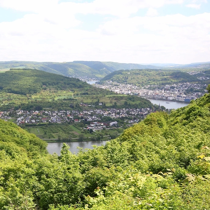 Landscape with hills, town and river under a blue cloudy sky