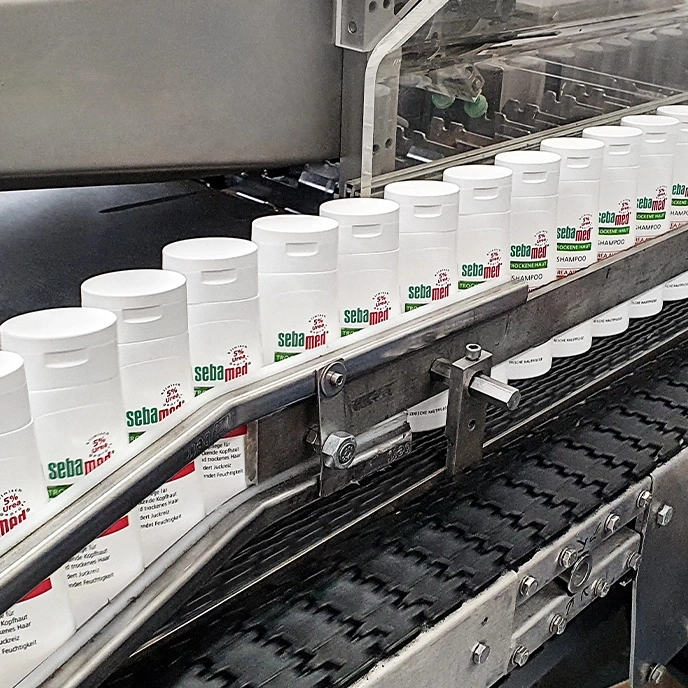 Sebamed shampoo bottles on a conveyor belt in a factory setting