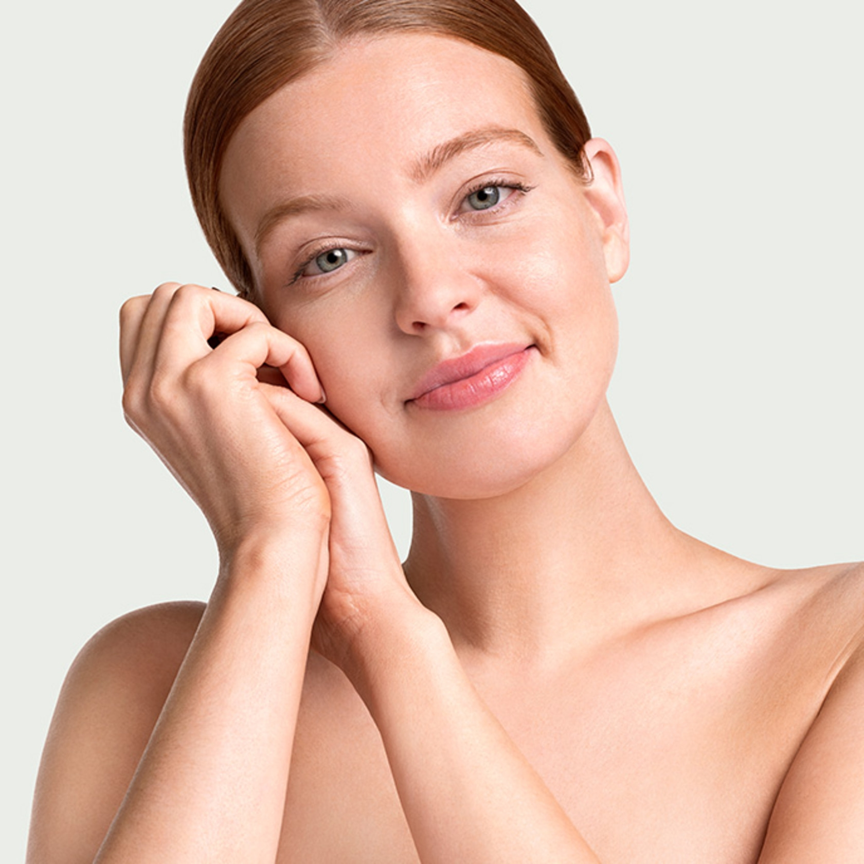 Portrait of a young woman smiling with hands near her face, looking at the camera.
