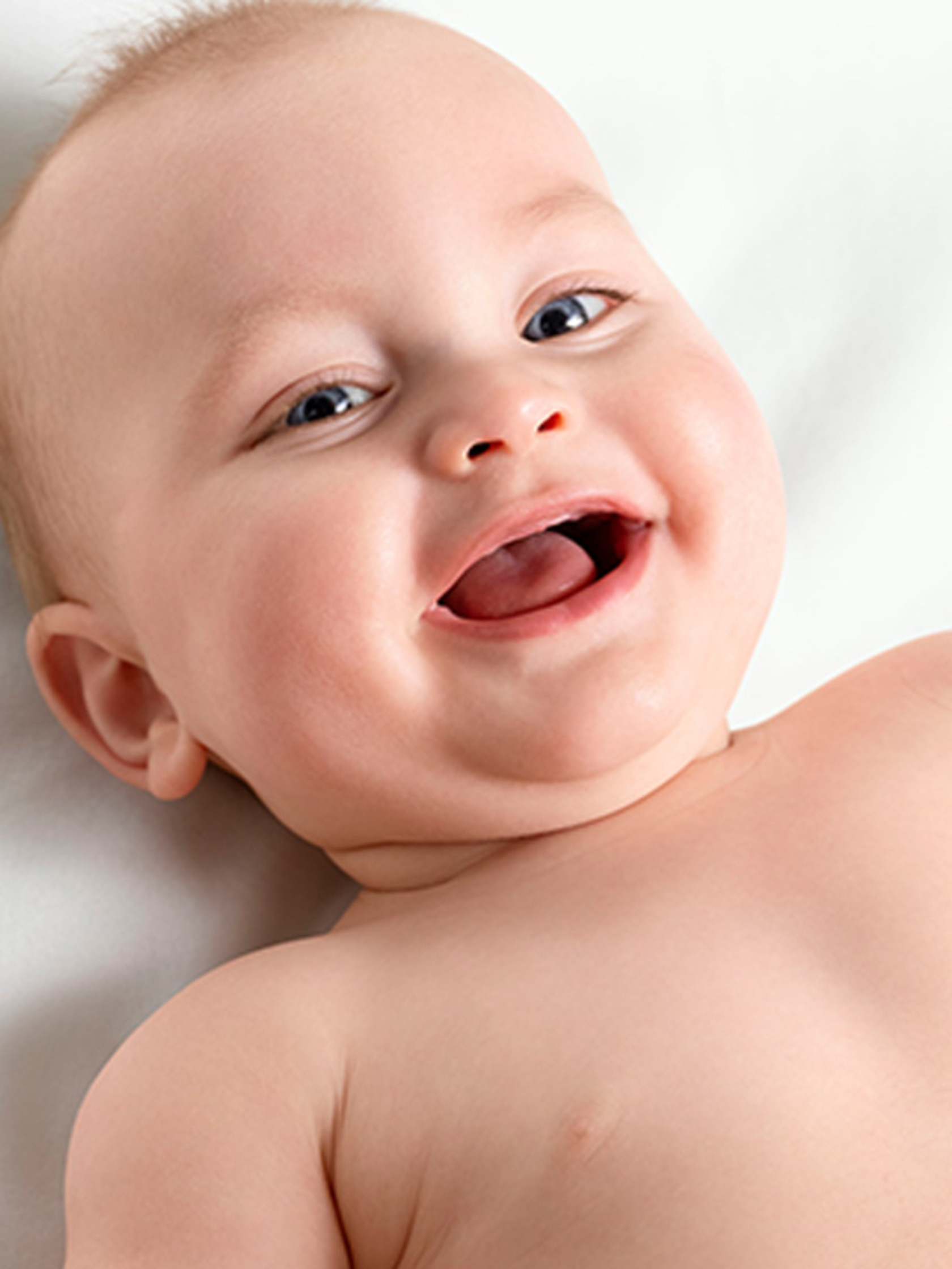 Ein glückliches Baby mit blauen Augen, das fröhlich in die Kamera lächelt und lacht.
