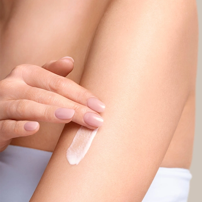 Nahaufnahme einer Person, die Creme auf ihren Arm aufträgt, Hautpflegekonzept.