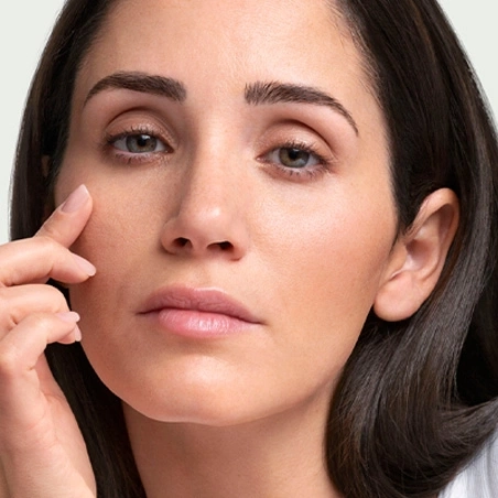Close-up of a woman touching her skin, with brown hair and eyes