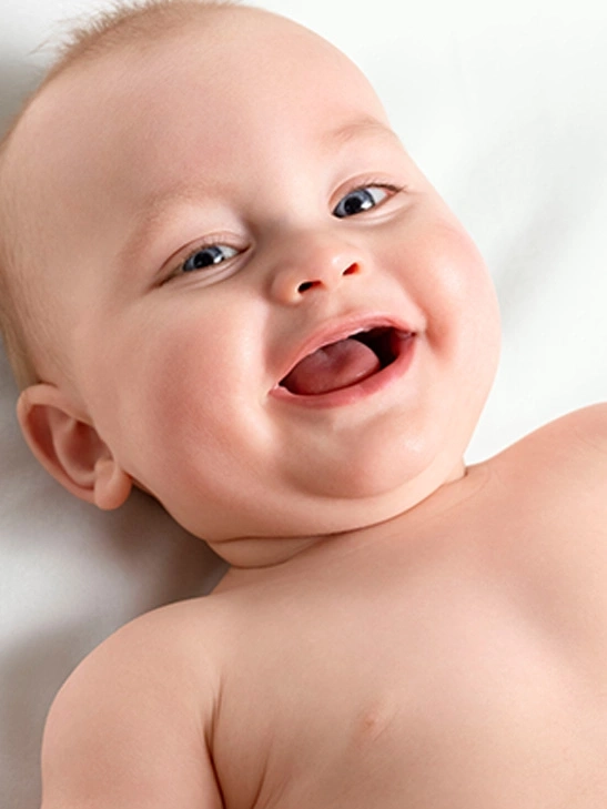 Ein glückliches Baby mit blauen Augen, das fröhlich in die Kamera lächelt und lacht.