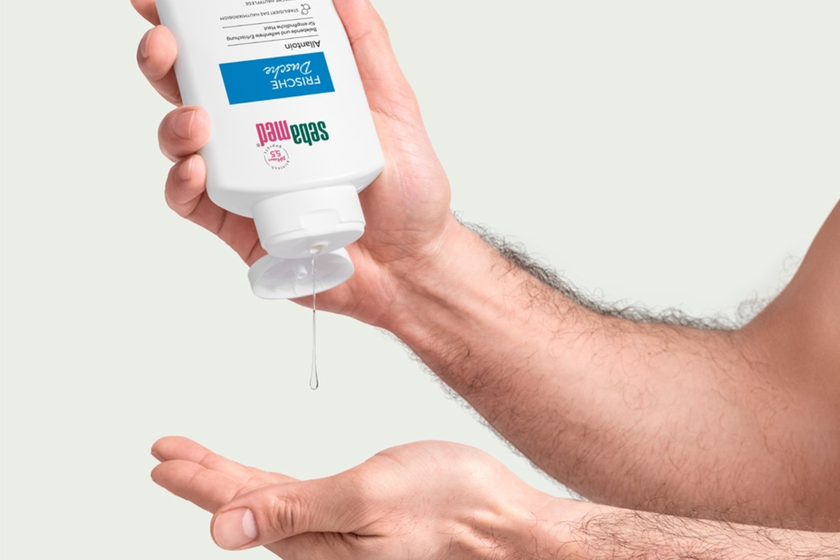 Person pouring liquid from a bottle into hand, skincare product.