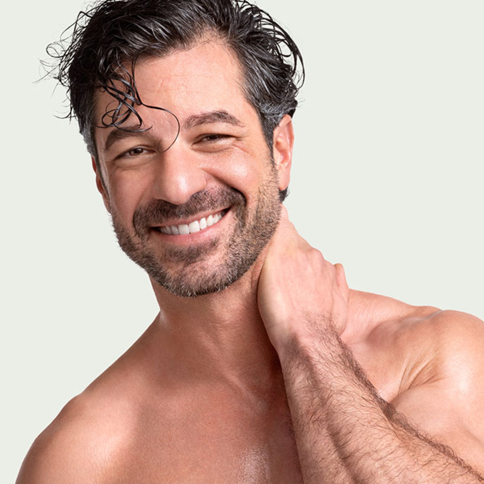 Smiling man with beard touching neck. Healthy and happy.