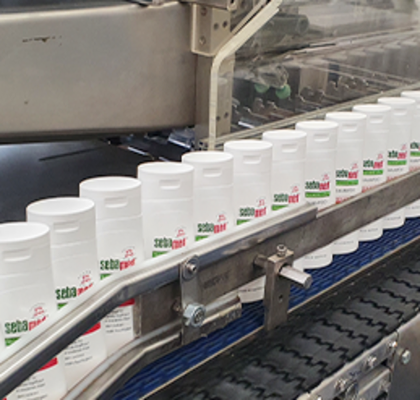 Sebamed bottles on a conveyor belt in a factory setting.